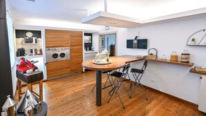 Een moderne keuken met houten kastjes, een ingebouwde oven en een eethoek met een ronde tafel en stoelen.