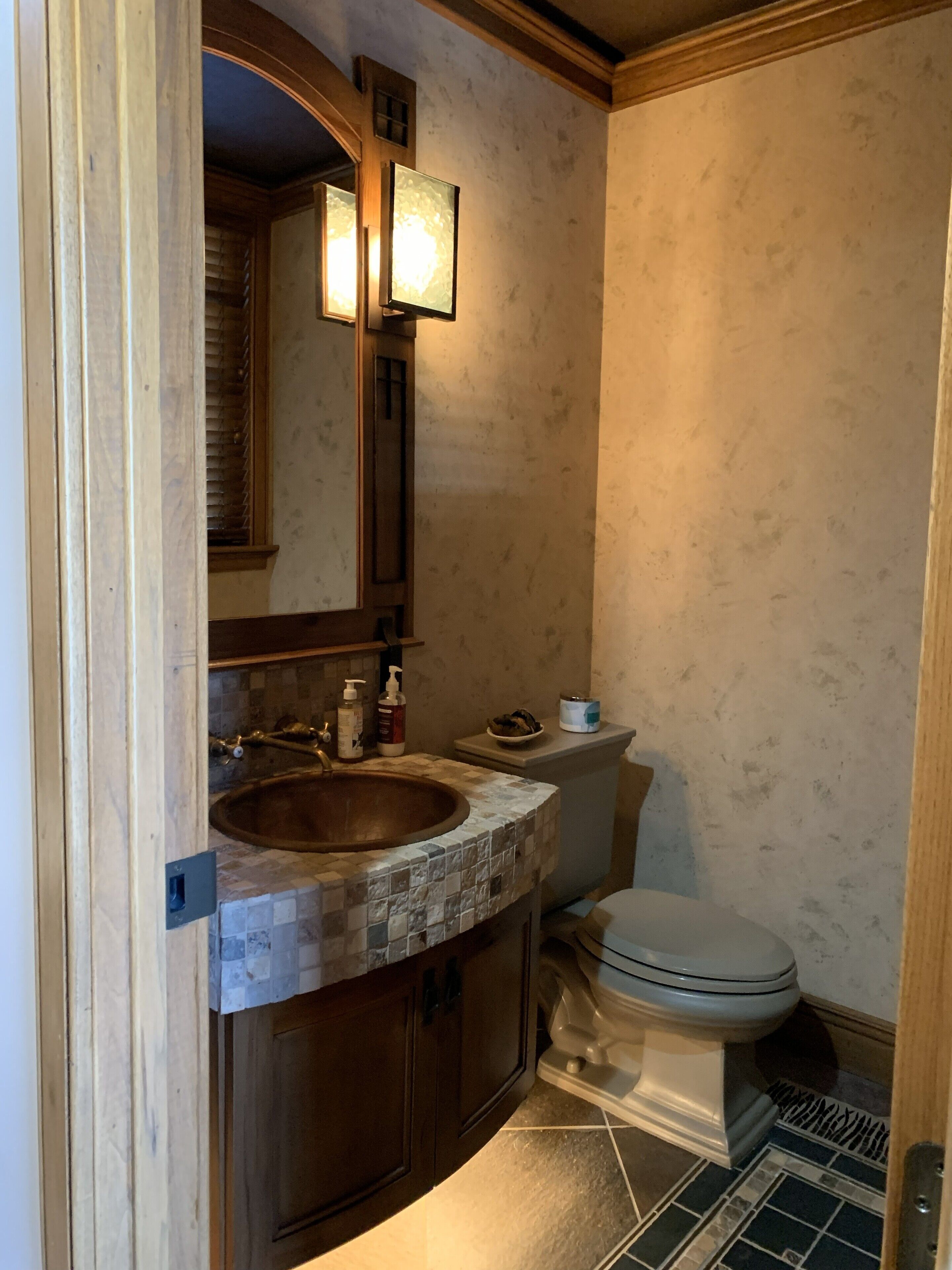 Een badkamer met een houten wastafelmeubel, een wastafel, een spiegel, een toilet en een douchehoek.
