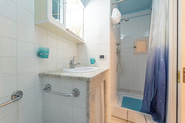 Un baño con lavamanos, espejo y ducha.