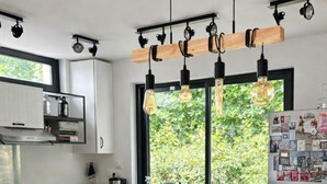 Cozinha moderna com bancada de madeira, luminárias pendentes e vista para o verde lá fora.