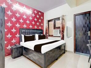 A hotel room with a bed, a nightstand, a wardrobe, a window with curtains, and a door. - Collection O Nehru Nagar (Ghaziabad)