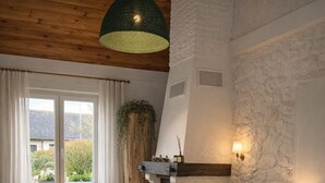 A cozy living room with a stone fireplace, comfortable seating, a television, and a large window with curtains. - La Villa Bellerose is a cosy Zen gîte on the Côte d'Opale, near Le Touquet. (Beutin)