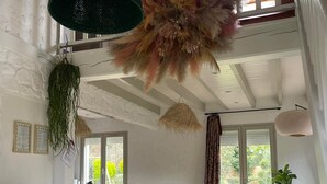 A spacious living room with a high ceiling, wooden beams, a large dining table, and a comfortable sofa. - La Villa Bellerose is a cosy Zen gîte on the Côte d'Opale, near Le Touquet. (Beutin)
