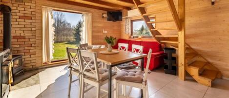A wooden interior with a dining area, a red sofa, and a fireplace.