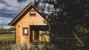 Una piccola baita di legno con tetto a spiovente, una porta d'ingresso e un piccolo finestrino.