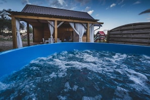 A hot tub with a wooden deck and a covered seating area. - Holiday home, private sauna and jacuzzi (Balachy)