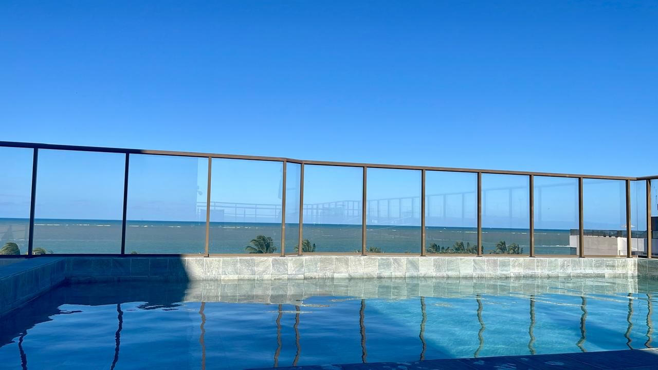 Una piscina infinita con vistas claras al océano y un puente a lo lejos.