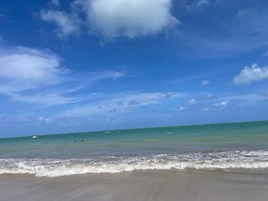 Een strand met heldere lucht en rustig water.