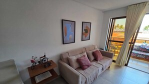 Un salon moderne avec un canapé, une petite table sur laquelle se trouvent un vélo et un livre, et deux tableaux abstraits accrochés au mur.