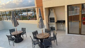Une terrasse extérieure avec des tables et des chaises rondes, un four en briques et une vue sur la ville.