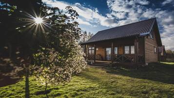 Uma cabana de madeira com telhado inclinado, varanda e um gramado.