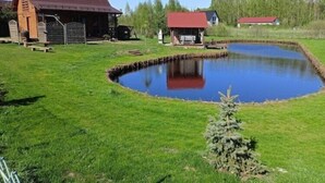 Uma propriedade campestre com lago, construções de madeira e um pequeno pinheiro de Natal.