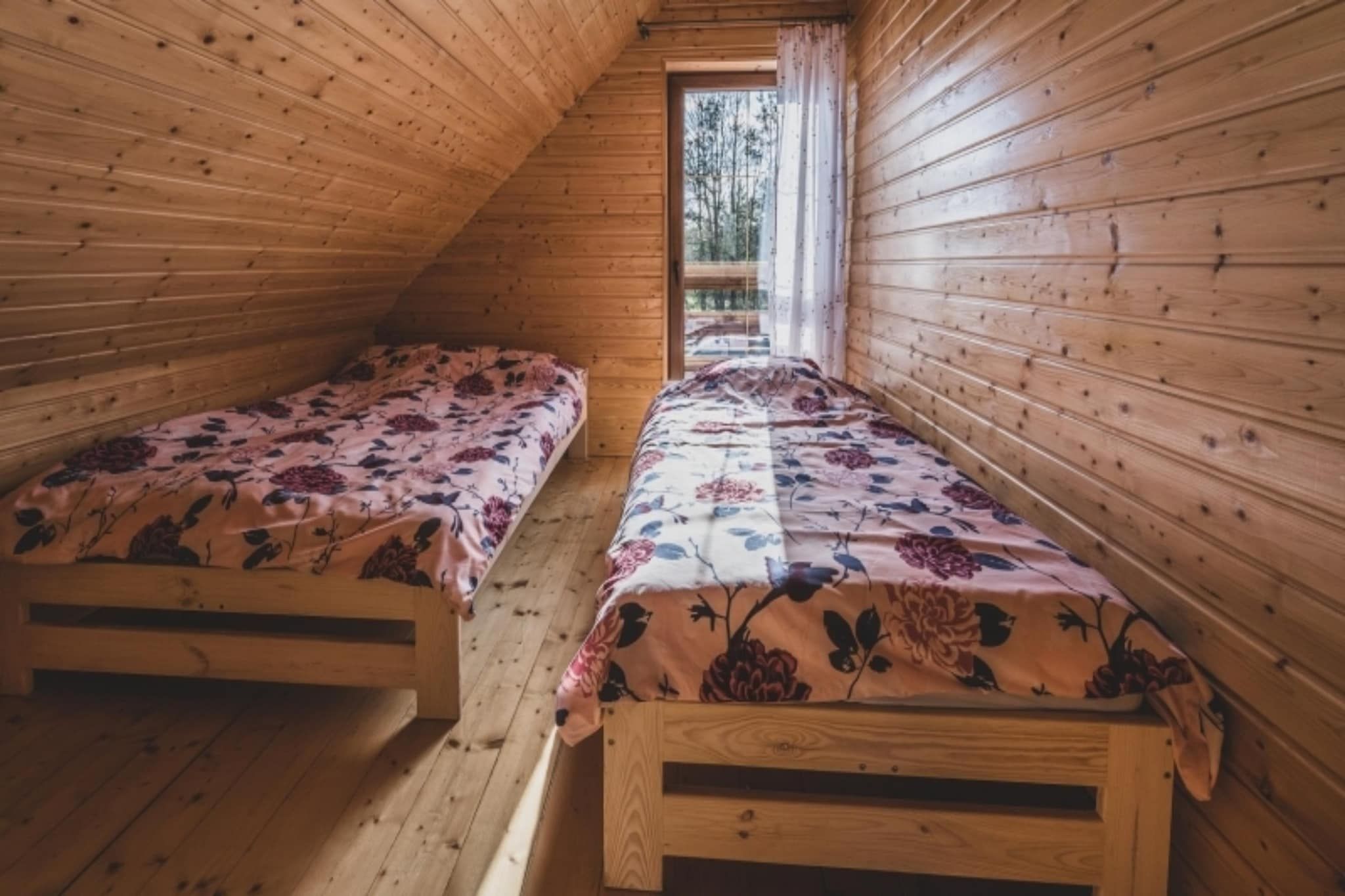 Una cabana amb dos llits superposats de fusta, un sostre inclinat i una finestra que ofereix vistes a l'exterior.