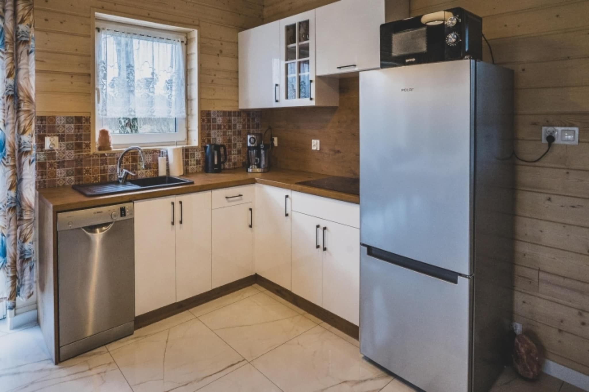 Een keuken met een roestvrijstalen koelkast, een koffiezetapparaat en een magnetron bovenop de koelkast.