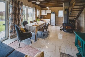 A dining area with a table set for four, surrounded by chairs, a kitchen in the background, and a staircase leading to an upper level. - Large holiday home, jacuzzi, sauna, salt cave (Balachy)