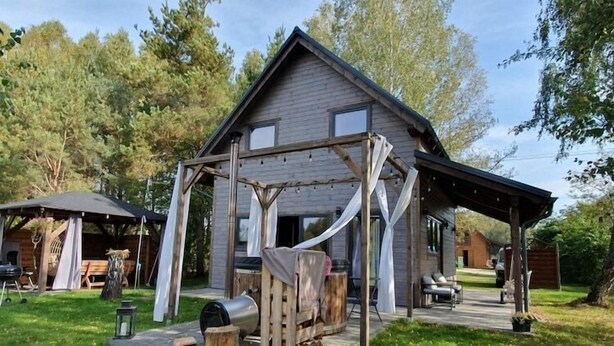 A rustic cabin with a wooden deck, a covered outdoor seating area, and a large window. - Large holiday home, salt cave, jacuzzi, sauna (Balachy)