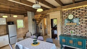 A cozy wooden cabin interior with a dining table, chairs, a kitchen area, and a decorative clock on the wall. - Large holiday home, salt cave, jacuzzi, sauna (Balachy)