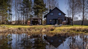 A house with a pond in front, surrounded by trees. - Large holiday home, salt cave, jacuzzi, sauna (Balachy)