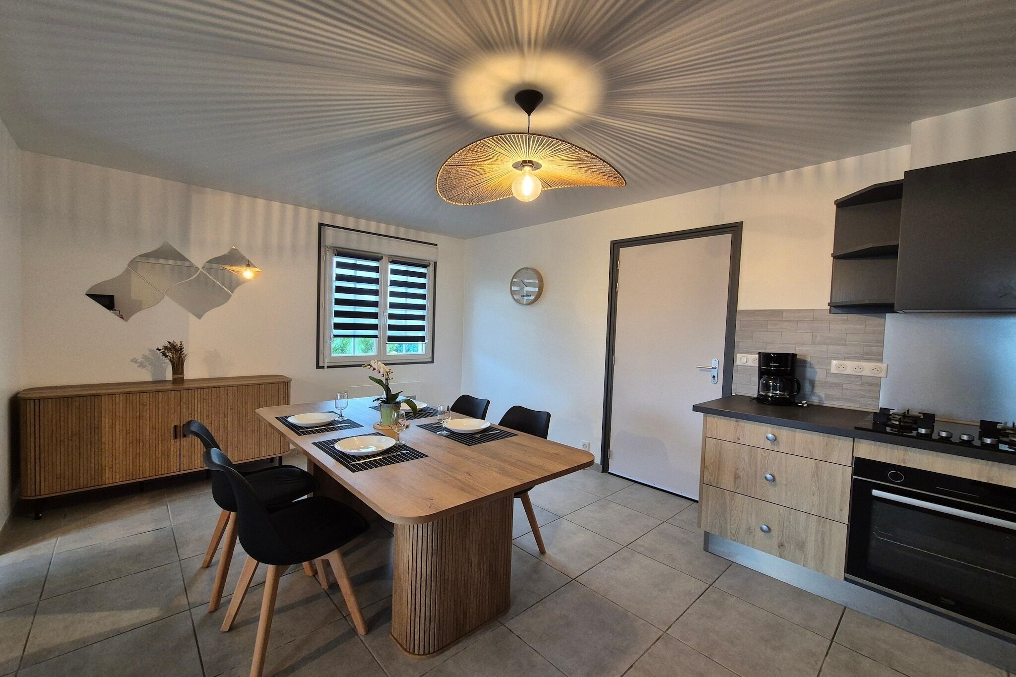 A modern kitchen with a dining area, wooden cabinets, and a unique ceiling light fixture.