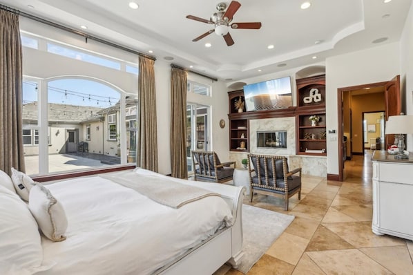 A spacious bedroom with a large bed, a ceiling fan, and a view of the outside.