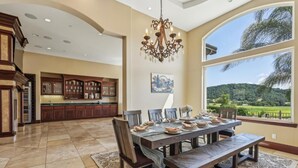 Un'ampia cucina con pensili in legno scuro, un grande tavolo da pranzo imbandito per sei persone e un lampadario.
