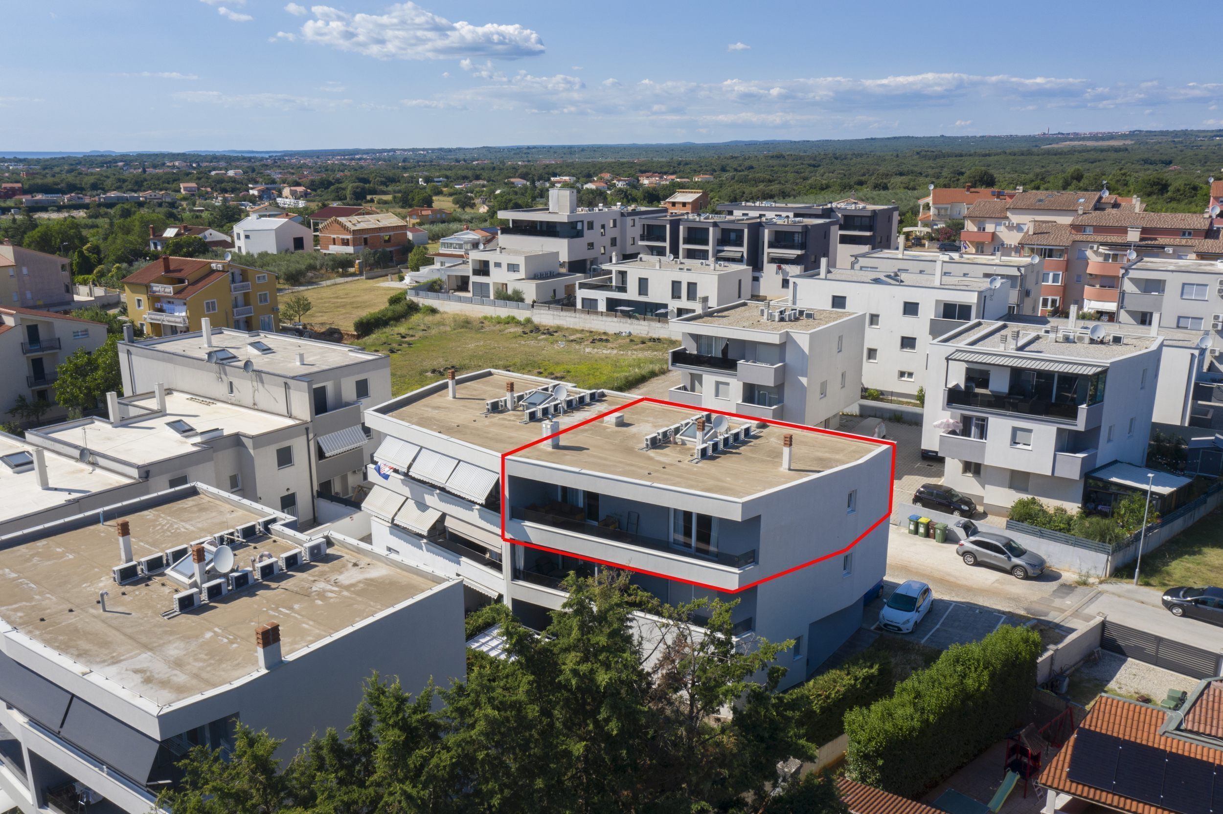 A residential area with modern buildings, a rooftop with satellite dishes, and a clear sky.