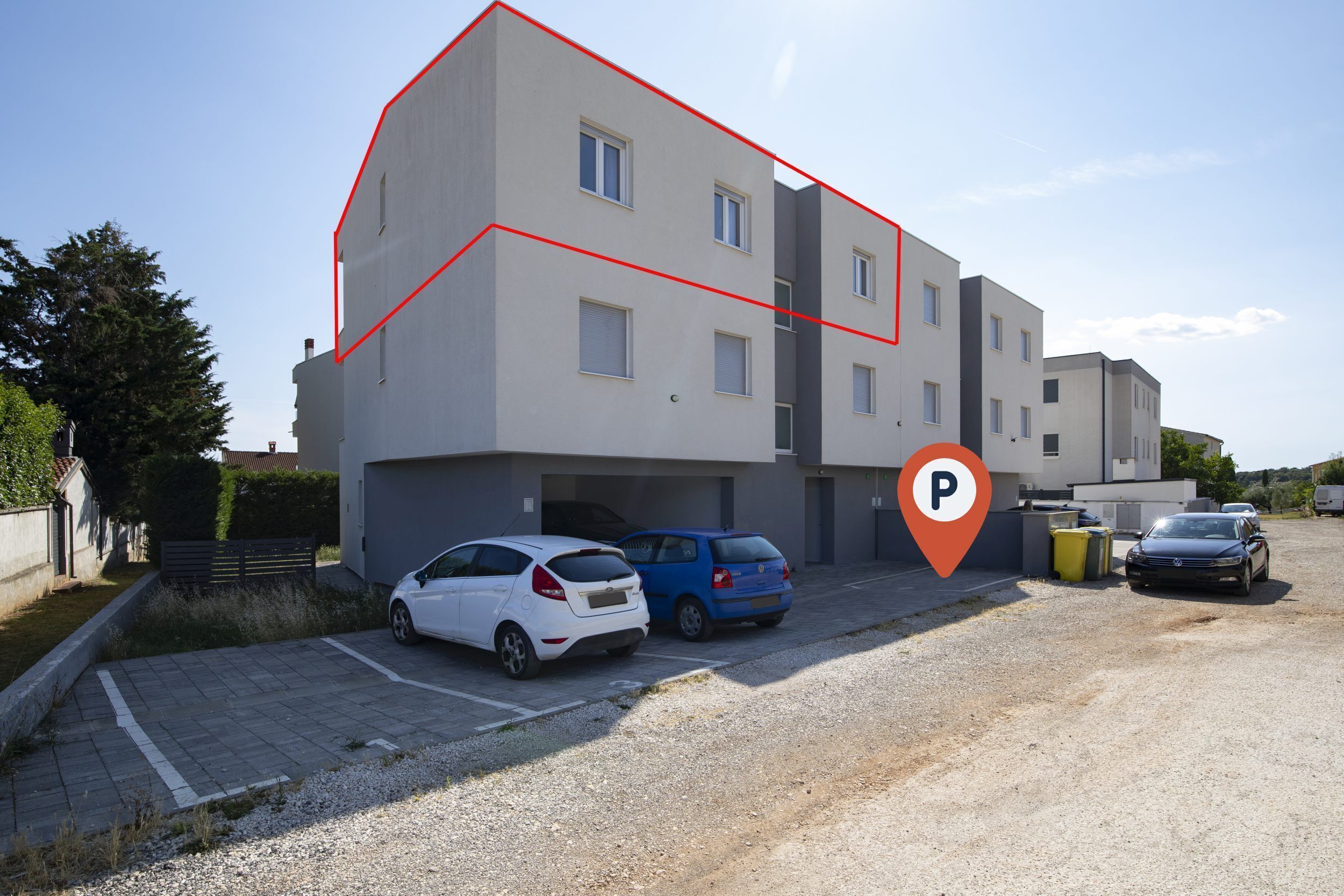 Un edifici residencial de diversos pisos amb una zona d'aparcament.