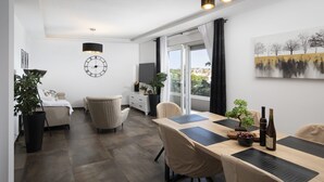 A modern living room with a dining area, a large window, and a clock on the wall. - Luxury Penthouse Pula (Pula)