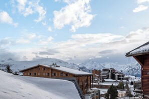 A snow-covered mountain town with wooden buildings and a clear sky. - Taiga – Central Apartment Near Slopes, Huez (Huez)