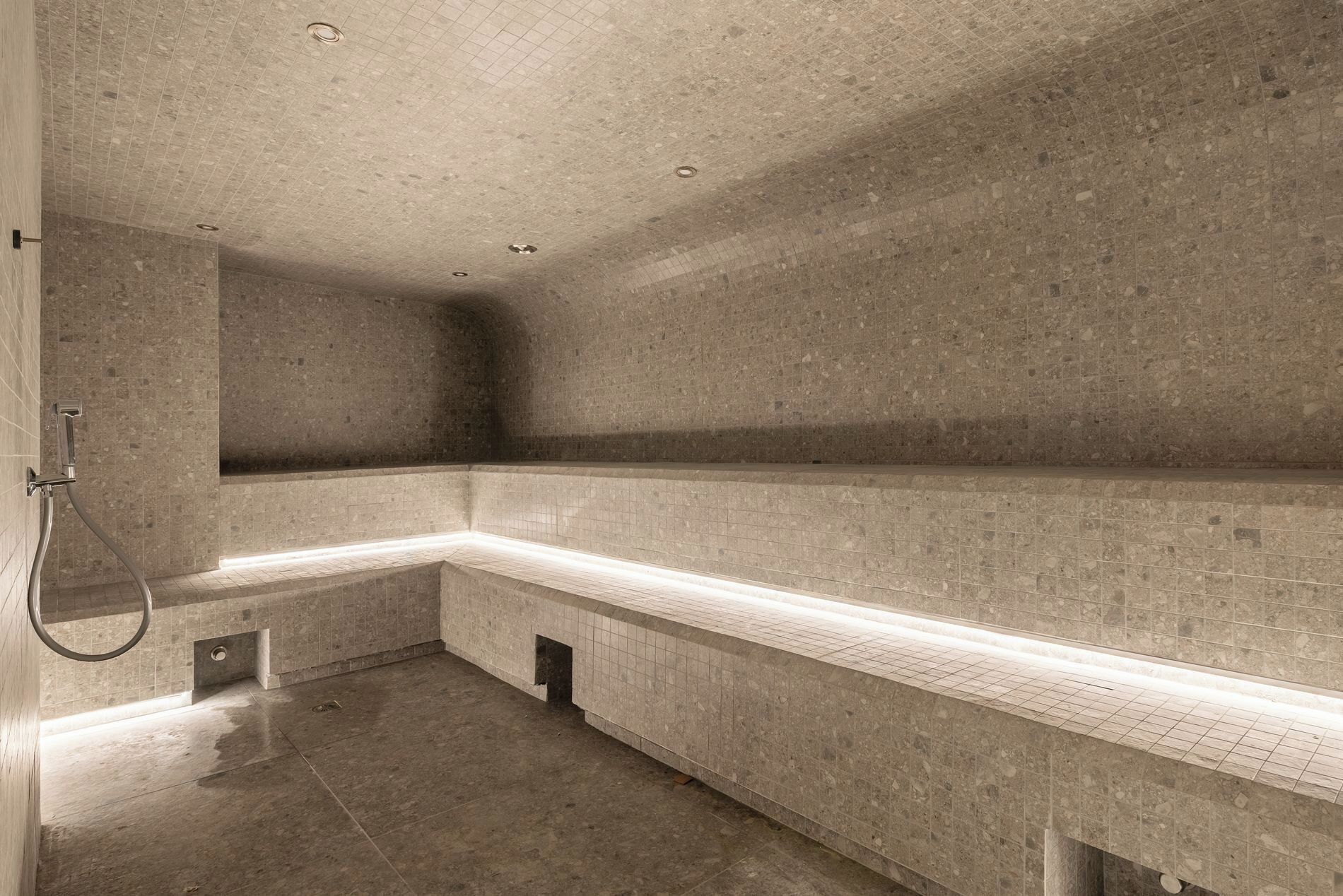 Une salle de bain moderne et minimaliste, dotée d’un grand banc incurvé et d’un espace douche.