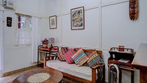 Um quarto com um sofá de madeira, uma mesa redonda e uma máquina de escrever antiga.