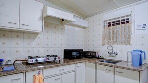 Cozinha com armários brancos, fogão a gás, micro-ondas e pia.