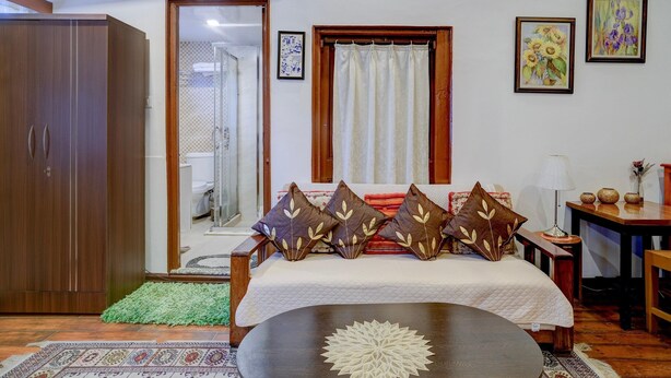 Quarto com uma cama, guarda-roupa de madeira, uma mesinha, abajur e duas quadros na parede.