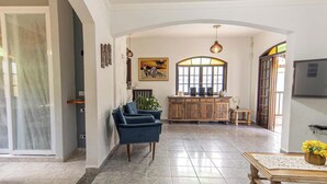 Uma sala de estar ampla, com um sofá azul, um armário de madeira e um espaço de jantar com mesa e cadeiras.