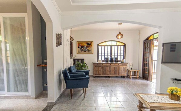 Un salón espacioso con un sofá azul, un armario de madera y un comedor con mesa y sillas.