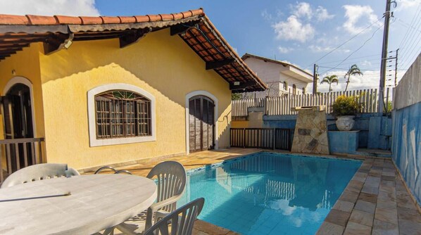 Il s’agit d’une propriété résidentielle dotée d’une piscine, d’une terrasse avec table et chaises, et d’un jardin clôturé.