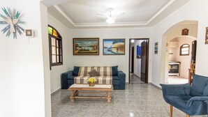 Uma sala de estar com sofá, uma mesa de centro com flores e duas pinturas na parede.