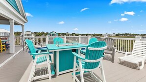 A covered outdoor deck with a table and chairs, a view of the surrounding area, and a railing. - Murrells Inlet - 163 It's Five O'Clock Somewhere (Murrells Inlet)