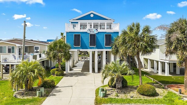 A two-story house with a balcony, a sign reading 'Marlin's Mermaid,' and a well-maintained front yard with palm trees. - Murrells Inlet - 163 It's Five O'Clock Somewhere (Murrells Inlet)