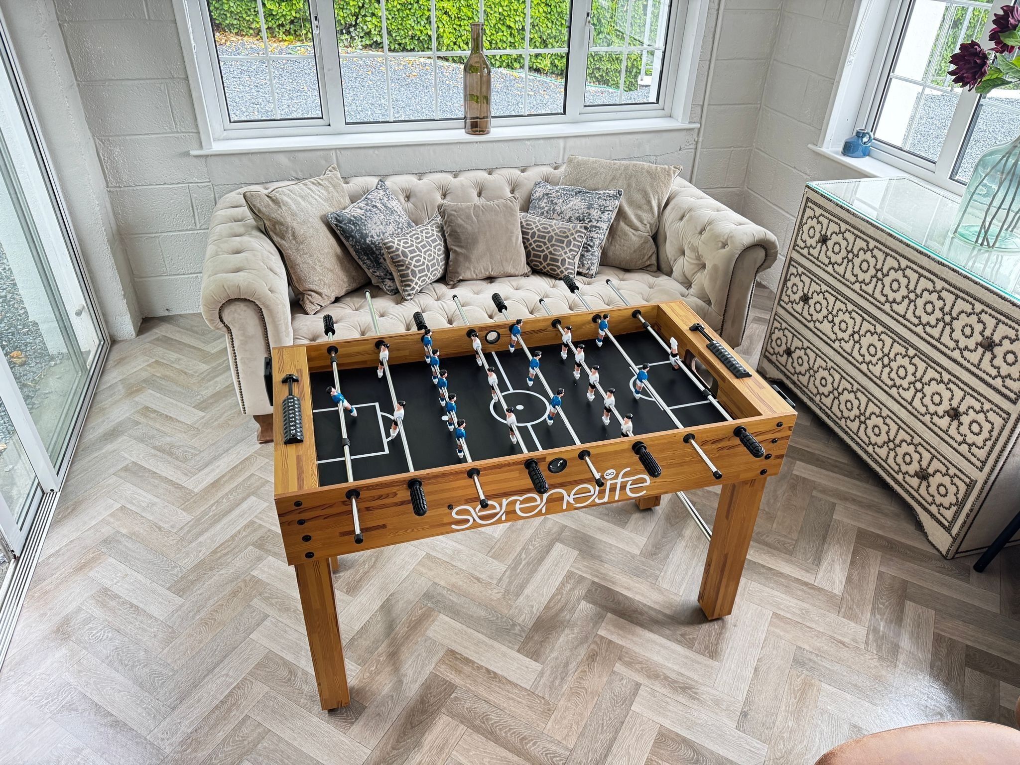 A foosball table in a room with a sofa and a cabinet.