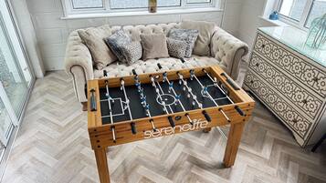 A foosball table in a room with a sofa and a cabinet.