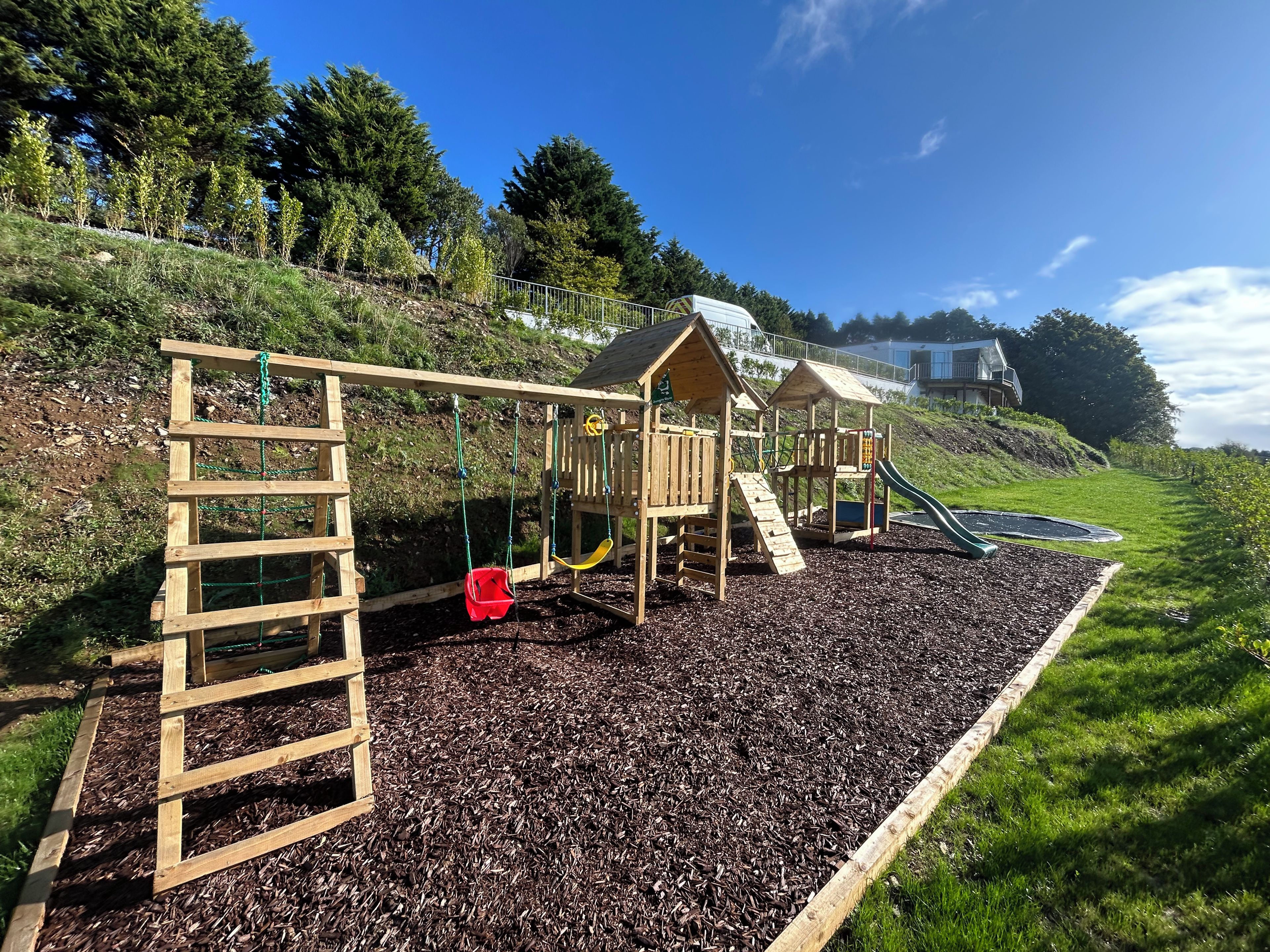 A playground with a wooden swing set, a slide, and a climbing structure.