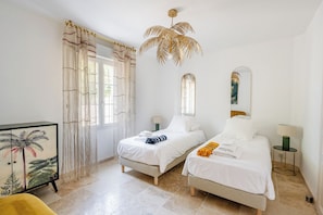 A room with two beds, a large window with curtains, a ceiling fan, and a framed picture on the wall. - Villa Sun 7, new at Crillon-le-Brave (Crillon-le-Brave)
