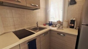 A compact kitchen with a sink, stove, and countertop. - Lights on the Sea (Alghero)