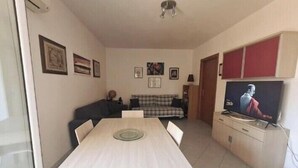 A living room with a dining table, sofa, and television. - Lights on the Sea (Alghero)