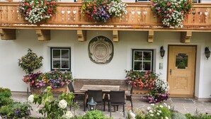 Een traditioneel gebouw met een houten balkon, een houten bank en een deur met een decoratief bord.