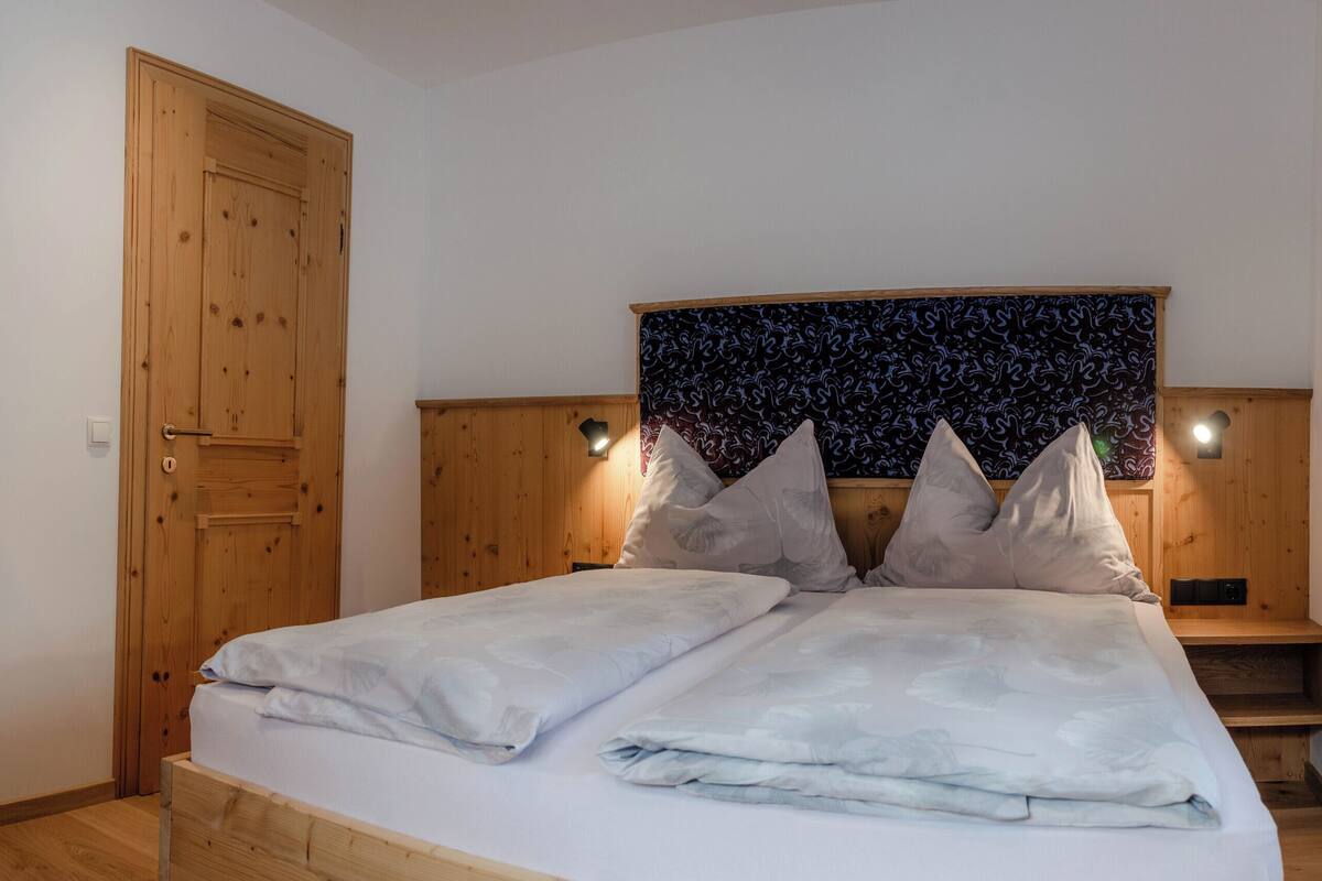 Ein Schlafzimmer mit einem Holzschrank, einem Bett mit gemustertem Kopfteil und einem Nachttisch.