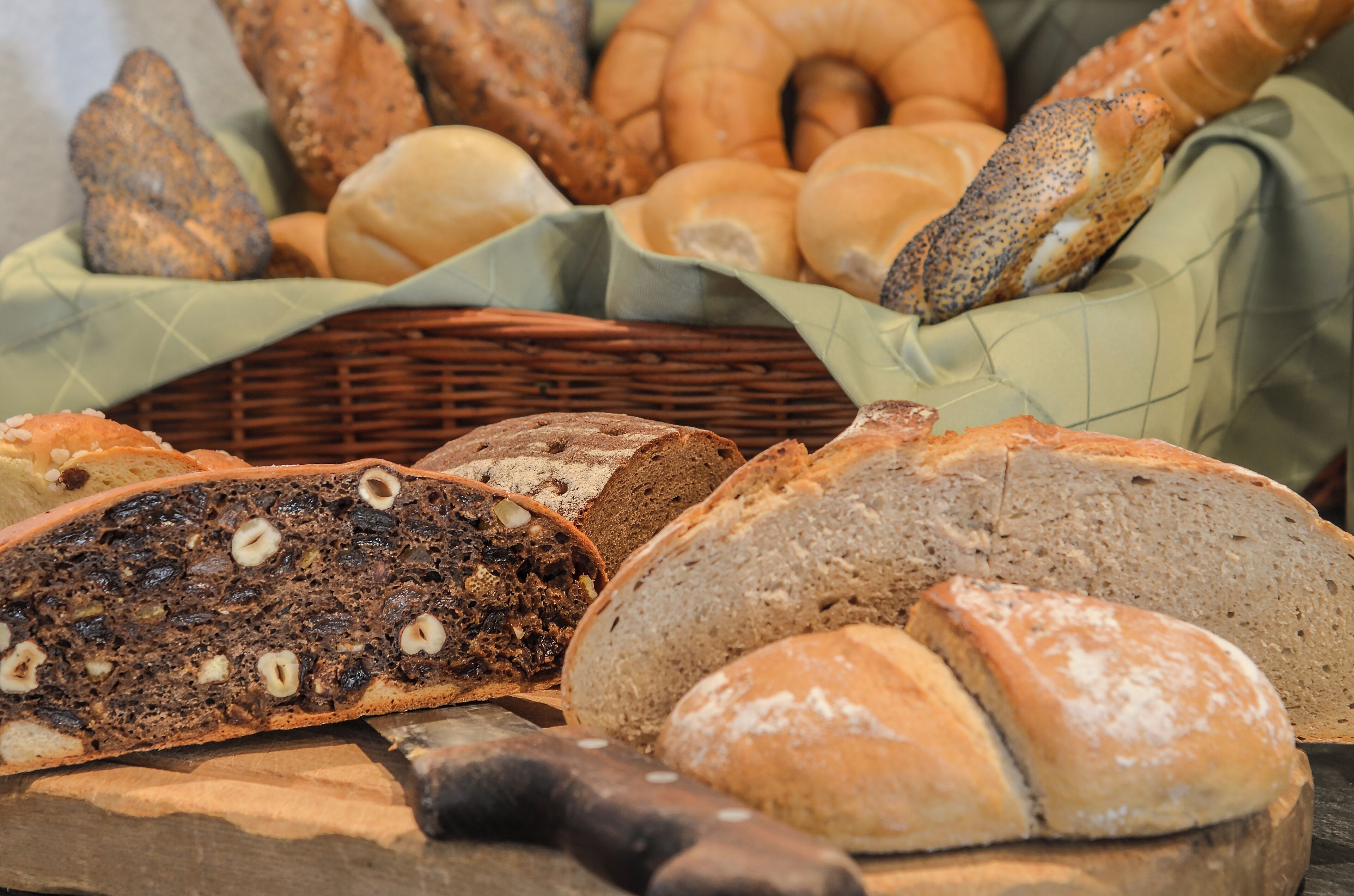 A variety of breads and pastries displayed on a wooden surface with a knife.