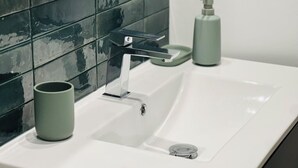 A bathroom with a white sink, a modern faucet, and a green soap dispenser. - CITY LOFT VALENCE HYPER CENTER (Valence)
