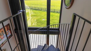 A staircase leading to a balcony with a view of a green field and a fence. - The Corn Silo (Ipswich)